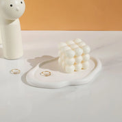 Nola Trinket Tray in cream, cloud-shaped, styled with gold rings and a bubble-textured candle