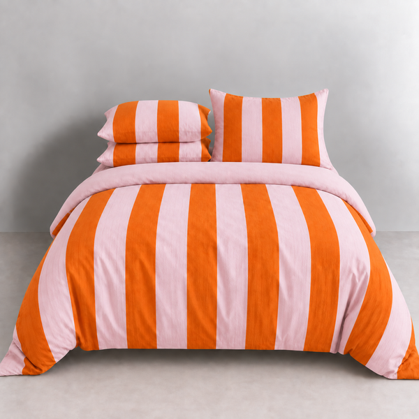 Ravello Stripe Bedding Set on a made bed, bold orange and pink stripes with matching pillowcases