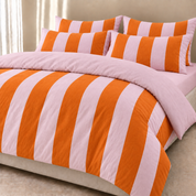 Ravello Stripe Bedding Set styled on a bed, wide orange and pink stripes with a crinkled, textured weave