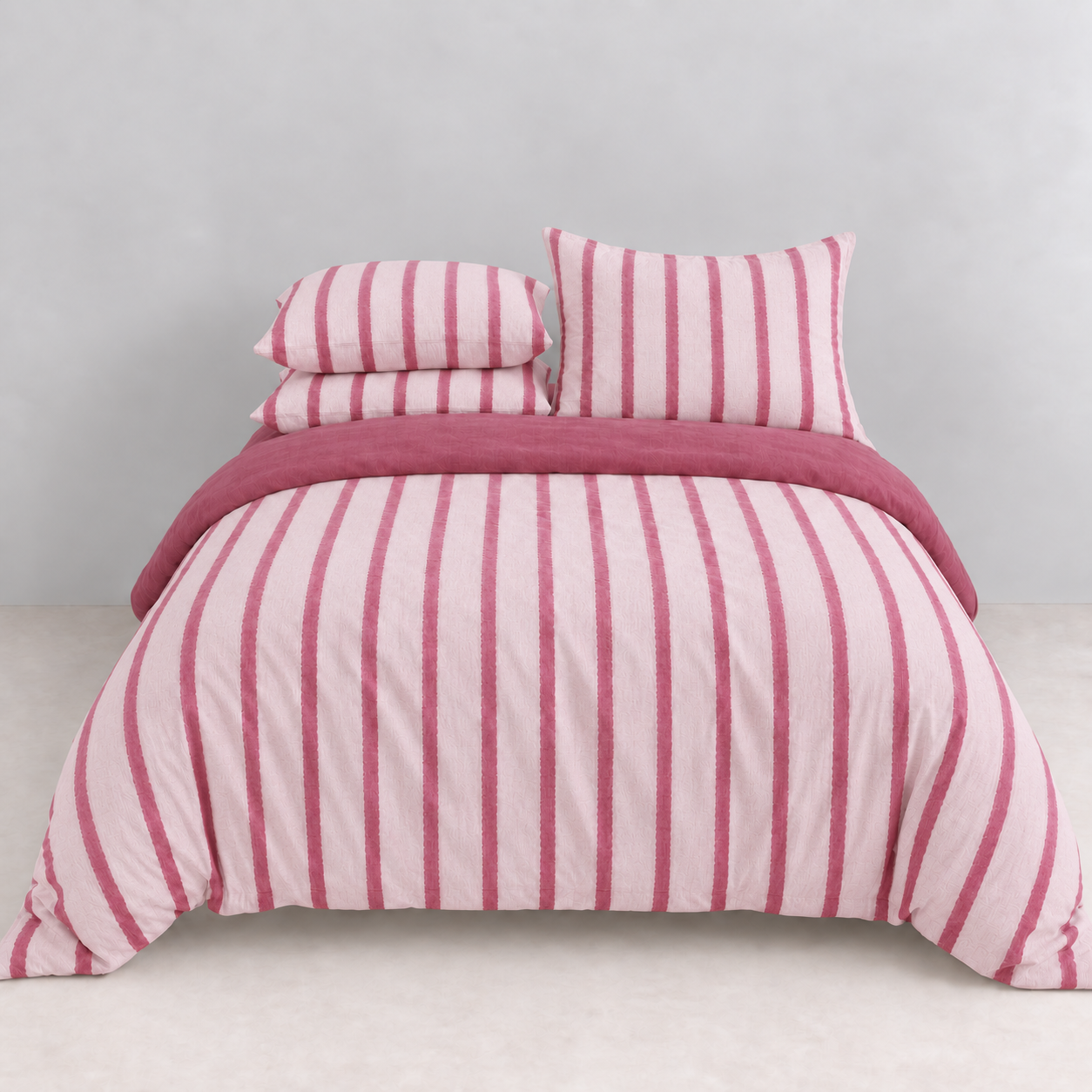 Rhodes Striped Bedding Set in Blush & Pink, made bed with pink stripes and a berry reverse trim