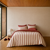 Rhodes Striped Bedding Set in Cherry & Cream on a made bed, with a red velvet cushion accent