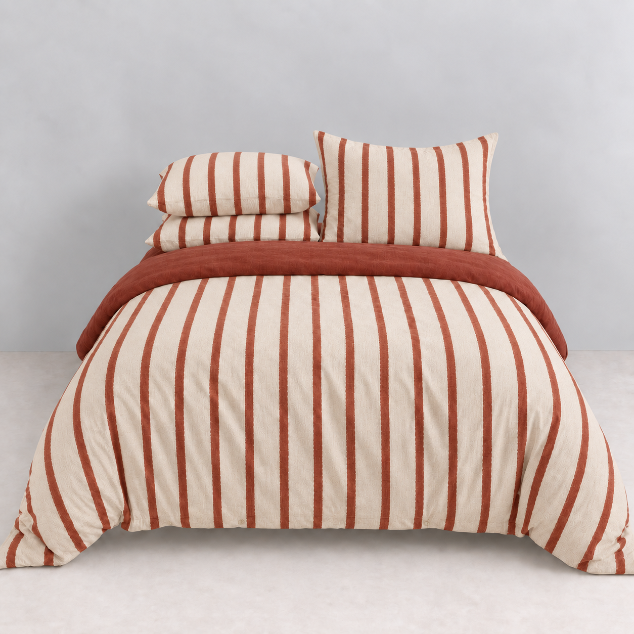 Rhodes Striped Bedding Set in Cherry & Cream, made bed with cream and red striped quilt cover and pillowcases