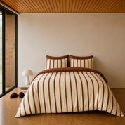 Rhodes Striped Bedding Set in Cocoa & Cream on a made bed, cream and brown stripes with a warm timber-ceilinged room