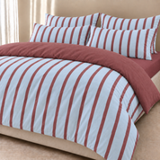 Rhodes Striped Bedding Set in Sky & Burgundy, quilt cover and pillowcases folded back on a made bed