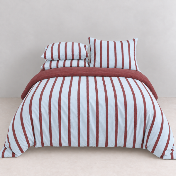 Rhodes Striped Bedding Set in Sky & Burgundy, made bed with striped quilt cover and matching pillowcases