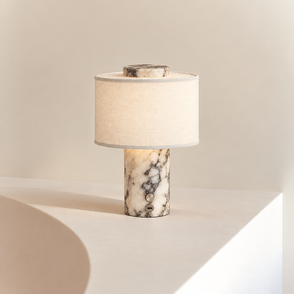 Romy Marble Lamp in Marble, grey veined stone base glowing beneath an ivory linen shade