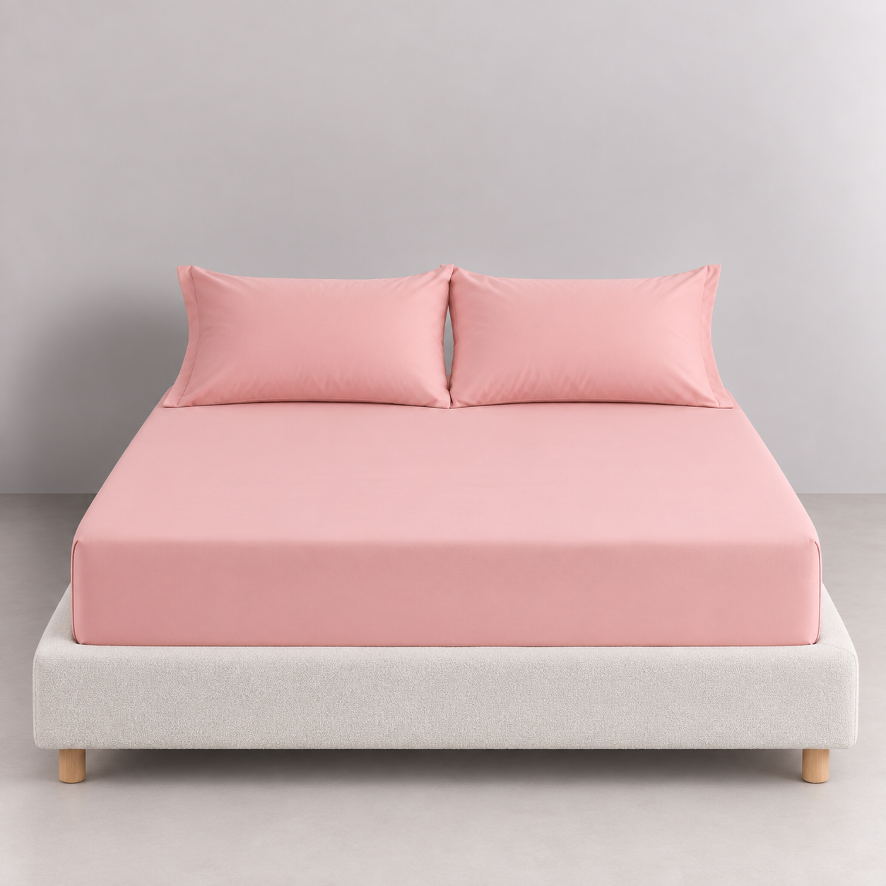 Sola Cotton Fitted Sheet in Blush, dressed on a bed with matching pillowcases, soft pink tone