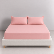 Sola Cotton Fitted Sheet in Blush, dressed on a bed with matching pillowcases, soft pink tone