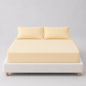 Sola Cotton Fitted Sheet in Butter, soft yellow cotton fitted to a bed with matching pillowcases