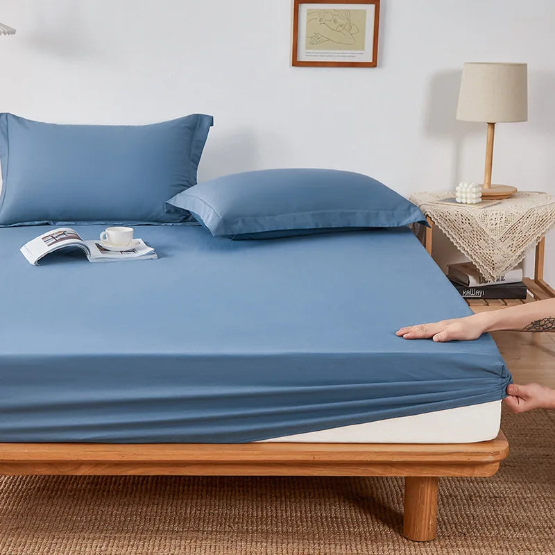 Sola Cotton Fitted Sheet in slate blue, hand pulling elasticated corner snug over mattress