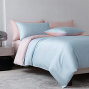 Soléa Bamboo Bedding Set in Blue Sky - Love Pink, sateen quilt cover and pillowcases on a made bed