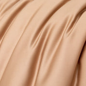 Close-up of the Soléa Bamboo Bedding Set in warm beige, showing the sateen weave's smooth sheen and soft folds