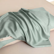 Soléa Bamboo Bedding Set in sage green, sateen fabric draped over pillows showing its smooth sheen