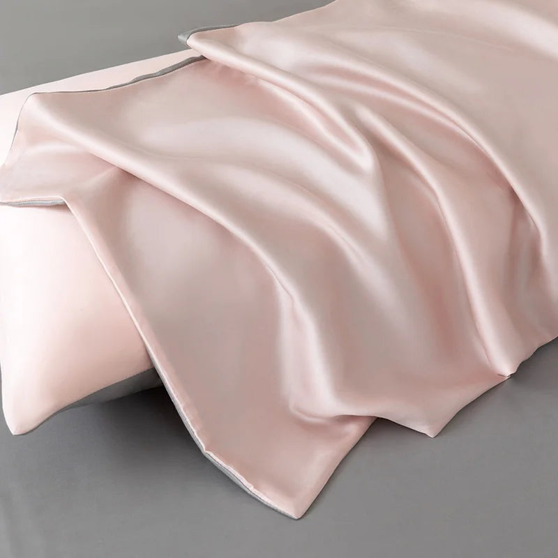 Close-up of the Soléa Bamboo Bedding Set in blush pink sateen, draped in soft folds over a pillow with grey trim