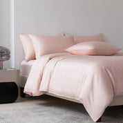 Soléa Bamboo Bedding Set in Love Pink, soft blush sateen dressing a bed beside a marble nightstand