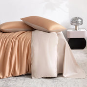 Soléa Bamboo Bedding Set in Rose Gold - Beige, sateen sheets draped beside a bed with soft folds