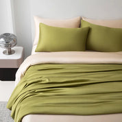 Soléa Bamboo Bedding Set styled bed, olive green sateen draped over beige sheets and pillowcases