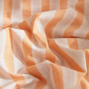 Close-up of the Soleil Stripe Bedding Set showing textured yarn-dyed stripes in soft orange and white cotton