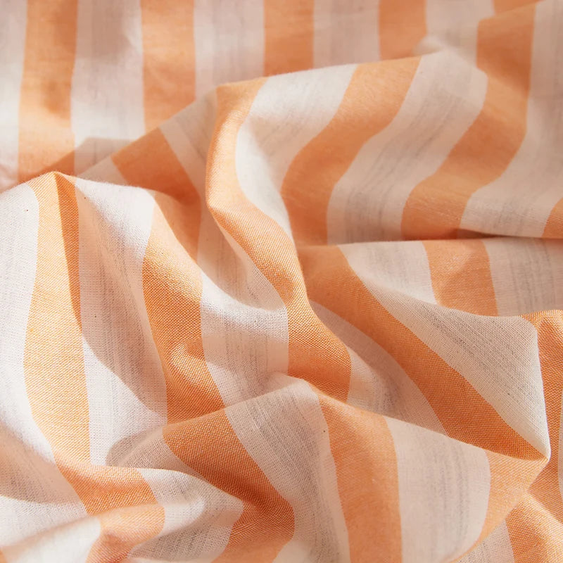 Close-up of the Soleil Stripe Bedding Set showing textured yarn-dyed stripes in soft orange and white cotton
