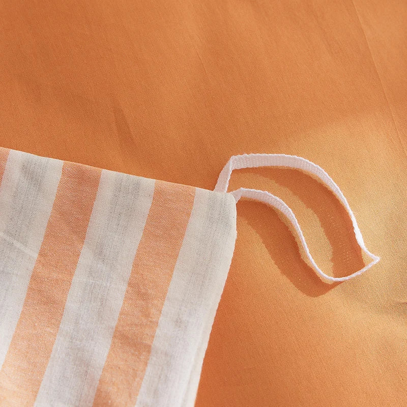 Close-up of the Soleil Stripe Bedding Set showing an inner tie against orange-striped cotton