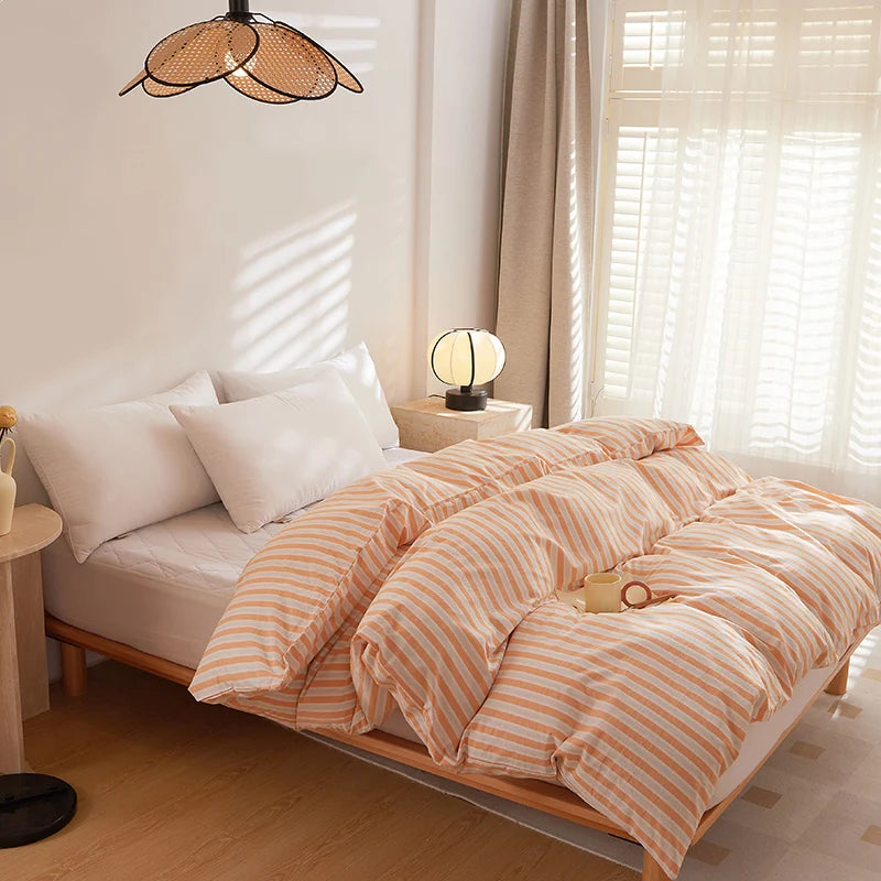 Soleil Stripe Bedding Set in soft peach and white stripes, styled on a bed by a sunlit window
