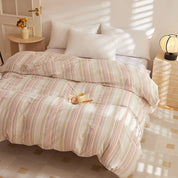 Soleil Stripe Bedding Set on a made bed, soft pink and green stripes in warm morning sunlight