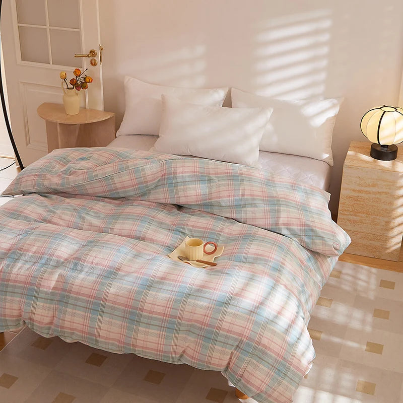Soleil Stripe Bedding Set styled on a made bed with soft pink and blue check pattern and white pillows in sunlit room