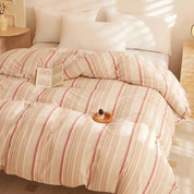Soleil Stripe Bedding Set styled with plump white pillows, soft coral and cream stripes in warm afternoon light