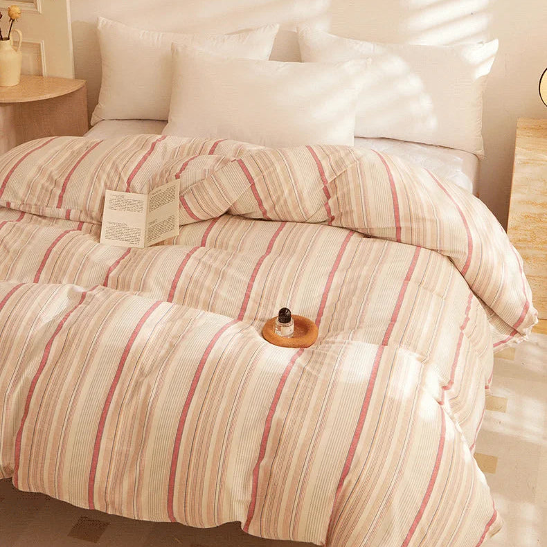 Soleil Stripe Bedding Set styled with plump white pillows, soft coral and cream stripes in warm afternoon light
