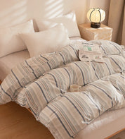 Soleil Stripe Bedding Set in cream and grey stripes, plumped on a bed with a newspaper and mug