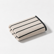 Folded hand towel from the Stay Soft™ Neutral Towel Collection in Beige, with black retro stripes