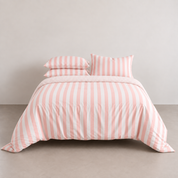 Striped Bedding Set in Pink, wide stripes on a made bed with matching pillowcases against a plain wall