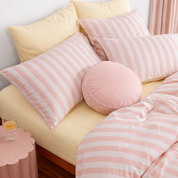 Striped Bedding Set in soft pink stripe, styled on yellow sheets with a round velvet cushion