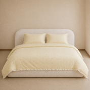 Sundae Spot Bedding Set in Custard Polka on a made bed, multicolour dots and a frilled cotton edge