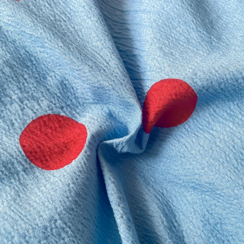 Close-up of the Ziggy Spot Bedding Set, cherry red spots on crinkled cotton blend fabric in soft blue