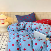 Ziggy Spot Bedding Set rumpled on a bed, cherry-red spots on soft blue with a navy pillowcase behind