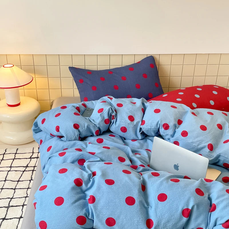 Ziggy Spot Bedding Set rumpled on a bed, cherry-red spots on soft blue with a navy pillowcase behind