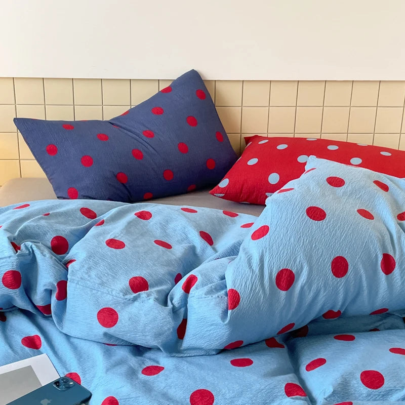 Ziggy Spot Bedding Set rumpled on a bed, cherry spots on sky blue with navy and red pillowcases
